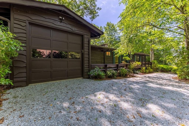 view of side of property with gravel driveway and a garage