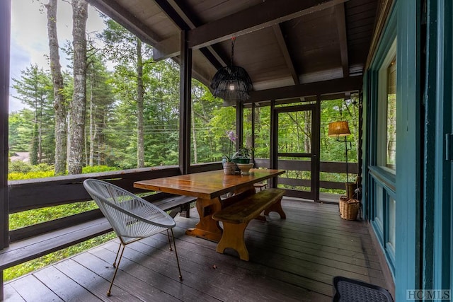 sunroom with outdoor dining area and beamed ceiling