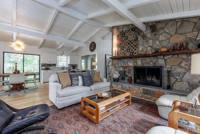 living room featuring lofted ceiling with beams, light wood-style flooring, and a fireplace
