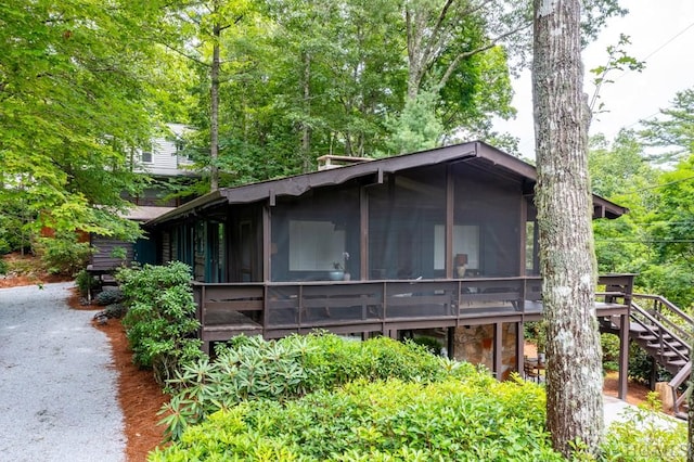 view of home's exterior featuring a wooden deck, a sunroom, and stairs