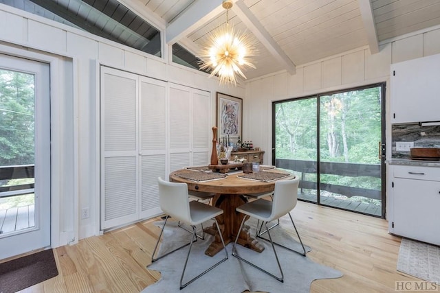 dining space featuring light wood-type flooring, wooden ceiling, an inviting chandelier, and beamed ceiling