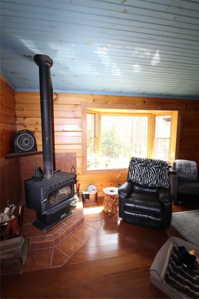 living area featuring wood walls, vaulted ceiling, wooden ceiling, a wood stove, and wood-type flooring