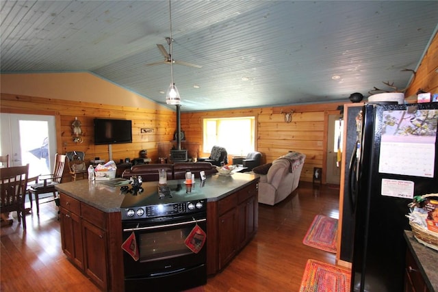 kitchen featuring black appliances, a wood stove, open floor plan, and dark wood-style flooring