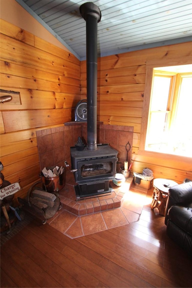 interior details featuring wood ceiling, wood finished floors, a wood stove, and wood walls