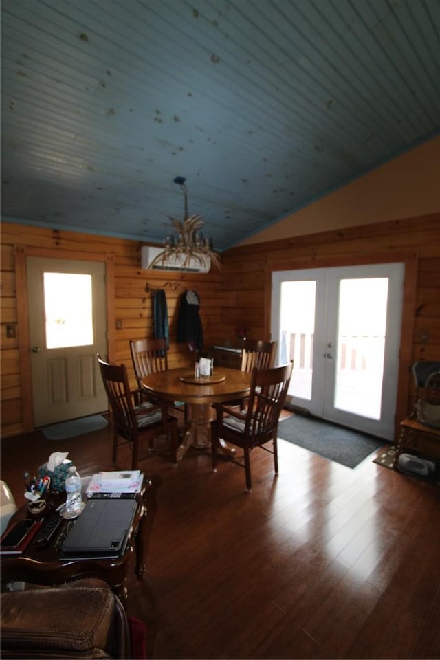 dining area featuring french doors, wood finished floors, vaulted ceiling, and wood walls