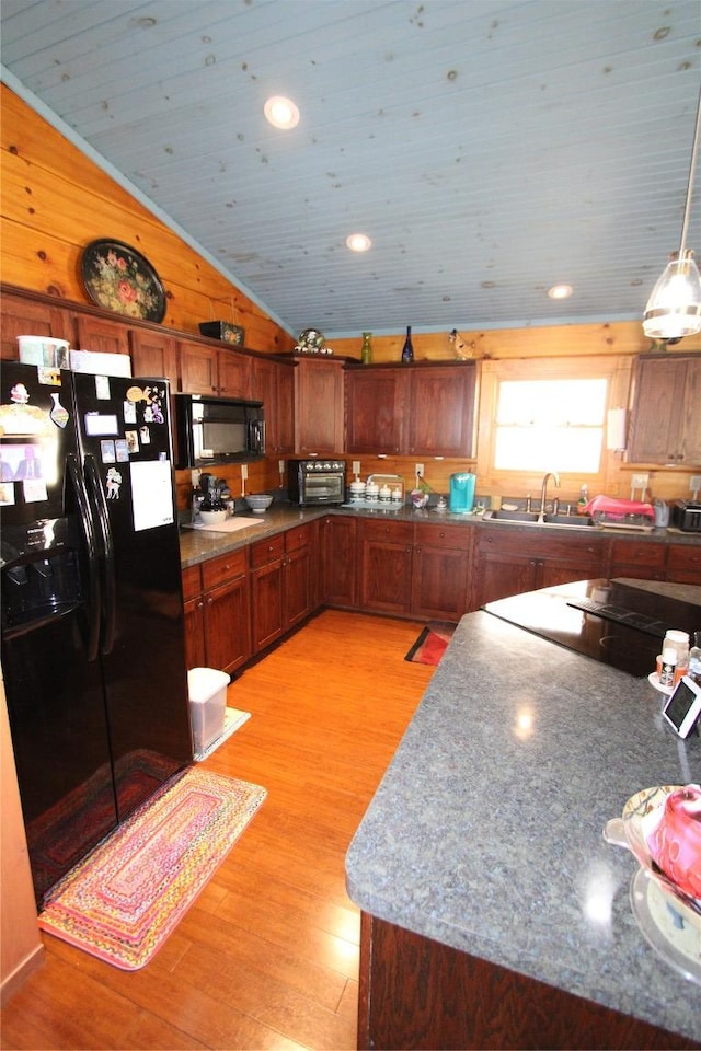 kitchen with wood walls, vaulted ceiling, brown cabinets, light wood-style floors, and black appliances