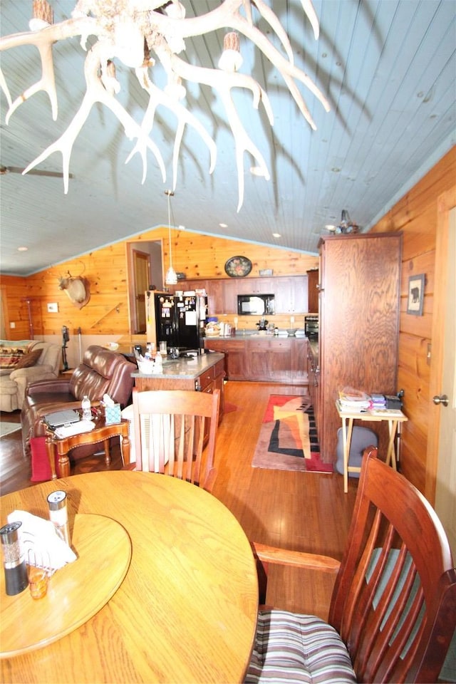 dining area with vaulted ceiling, light wood finished floors, wooden ceiling, and wood walls