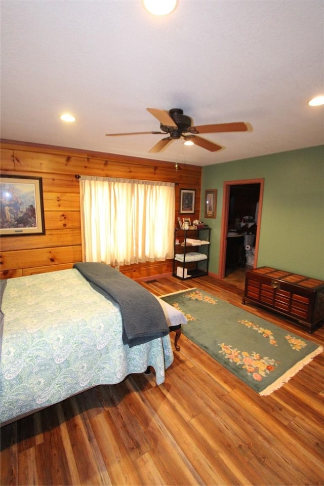 bedroom with wooden walls, recessed lighting, ceiling fan, and wood finished floors