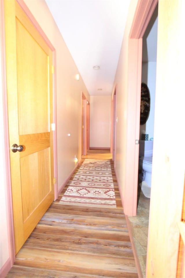 hall with light wood-style flooring and baseboards