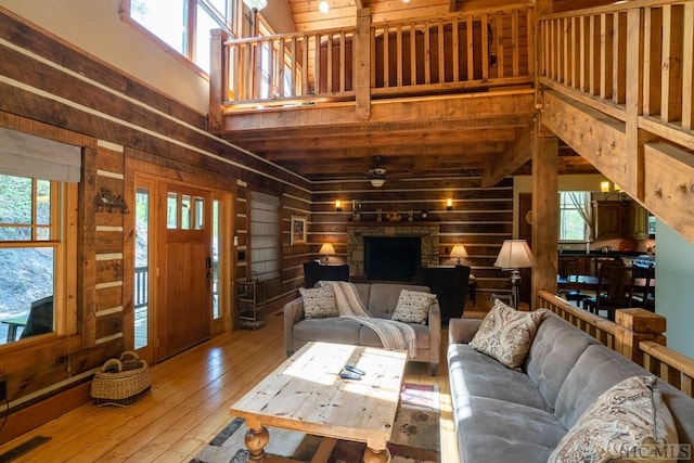 living room with hardwood / wood-style flooring, wooden walls, high vaulted ceiling, and ceiling fan