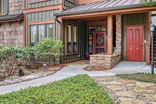 view of exterior entry with a standing seam roof, stone siding, board and batten siding, and metal roof