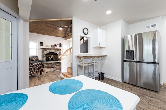 67 Chipmunk Trl, Glenville, NC 28736 - interior space with stainless steel fridge with ice dispenser, wood finished floors, white cabinetry, lofted ceiling, and a stone fireplace