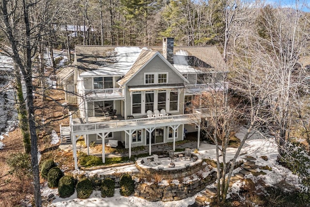 rear view of property featuring a balcony, a patio, a chimney, a fire pit, and a shingled roof