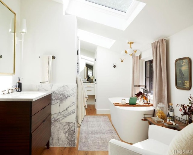 bathroom with hardwood / wood-style flooring, vanity, and a skylight