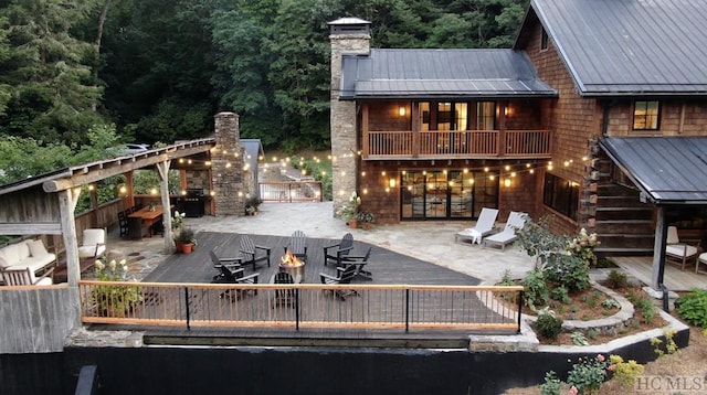 exterior space featuring a fire pit, a patio, a balcony, a fireplace, and a deck