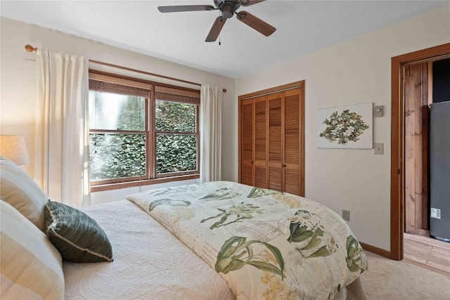 bedroom with a closet, ceiling fan, light colored carpet, and baseboards