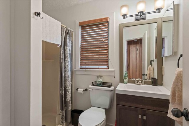 bathroom with a stall shower, toilet, and vanity