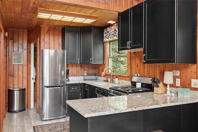 kitchen featuring stainless steel appliances, dark cabinets, wooden ceiling, light stone counters, and wood walls