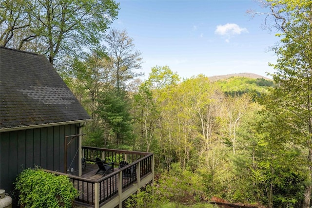 view of yard with a wooden deck and a view of trees