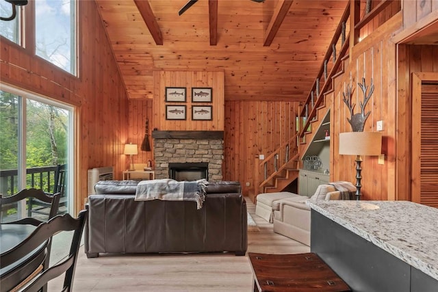 living room featuring stairway, wooden walls, high vaulted ceiling, wood ceiling, and light wood-style flooring