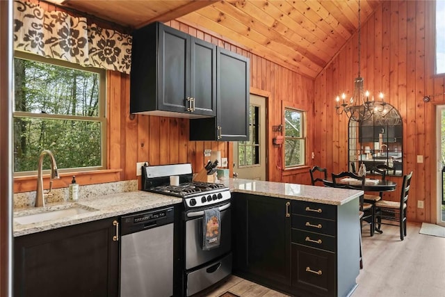 kitchen with appliances with stainless steel finishes, a sink, lofted ceiling, a peninsula, and a chandelier