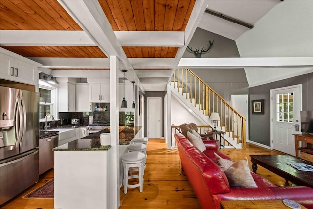living room with stairs, healthy amount of natural light, light wood-type flooring, and wooden ceiling