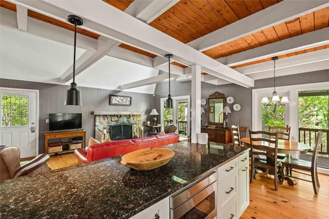 kitchen featuring beam ceiling, stainless steel microwave, light wood-style floors, white cabinetry, and open floor plan