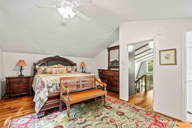 bedroom with lofted ceiling, wood finished floors, and a textured ceiling