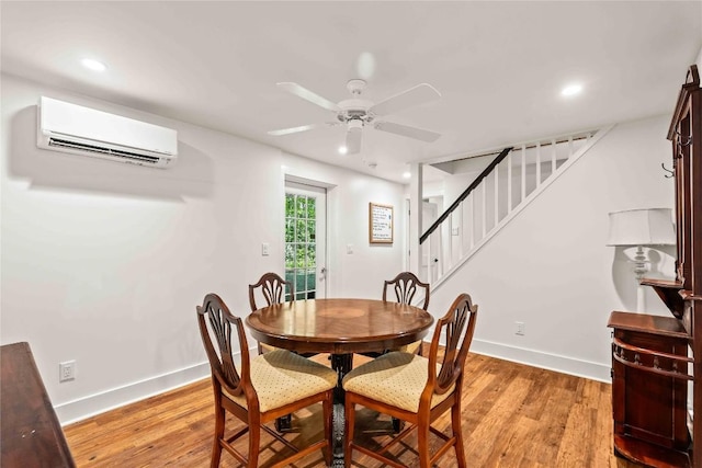 dining space with a wall mounted AC, stairs, baseboards, a ceiling fan, and light wood-style flooring