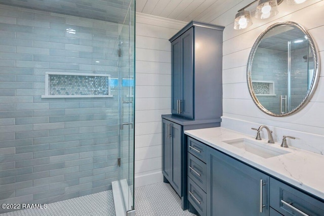 bathroom featuring a shower with door and vanity