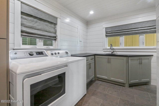 laundry room with separate washer and dryer, cabinets, wooden walls, dark tile floors, and sink