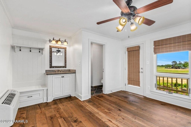 interior space with ceiling fan, dark wood-type flooring, ornamental molding, and ensuite bath