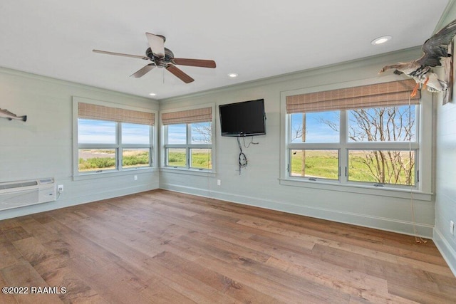 empty room featuring crown molding, light hardwood / wood-style floors, ceiling fan, and an AC wall unit