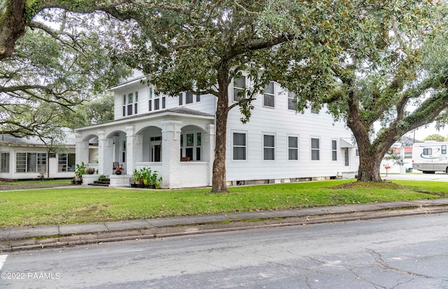 view of front of home with covered porch and a front lawn