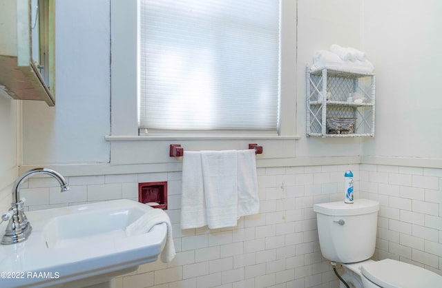 bathroom featuring tile walls, sink, and toilet