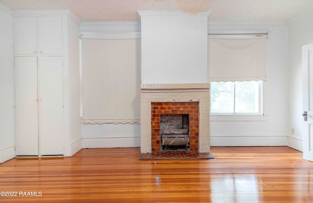 unfurnished living room with a brick fireplace, light hardwood / wood-style floors, and crown molding