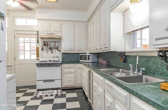 kitchen featuring dark tile flooring, plenty of natural light, ornamental molding, white gas range oven, and white cabinetry