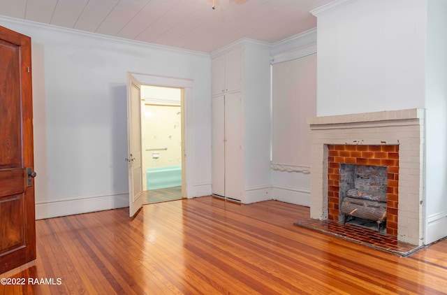 unfurnished living room with a brick fireplace, ornamental molding, and light wood-type flooring