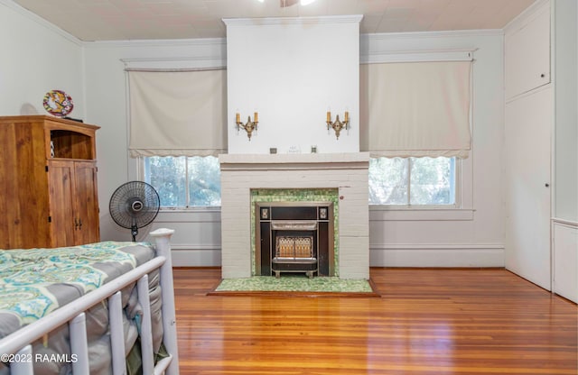 bedroom with multiple windows, a brick fireplace, ornamental molding, and wood-type flooring