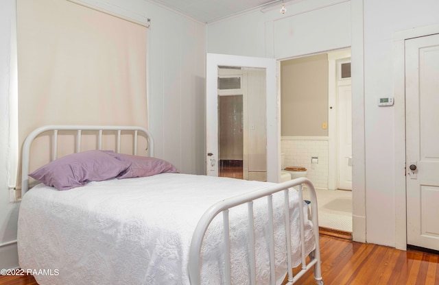 bedroom featuring ensuite bath, ornamental molding, and light hardwood / wood-style floors