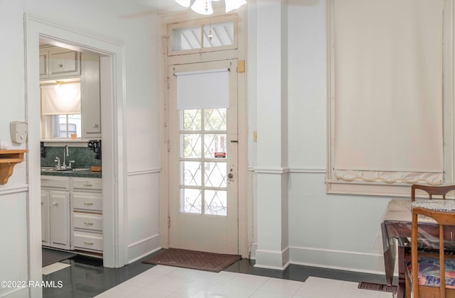 doorway to outside with dark tile floors, sink, and a healthy amount of sunlight