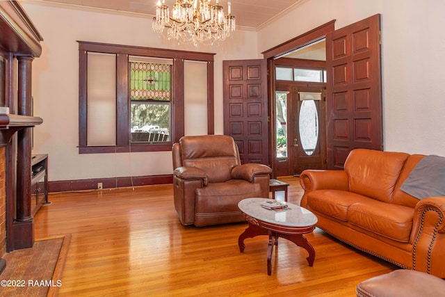 living room with a notable chandelier, decorative columns, light hardwood / wood-style flooring, and crown molding