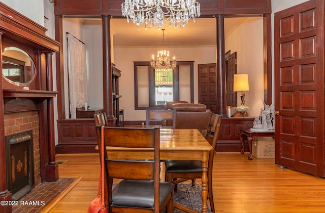 dining area with ornamental molding, a chandelier, decorative columns, and light wood-type flooring