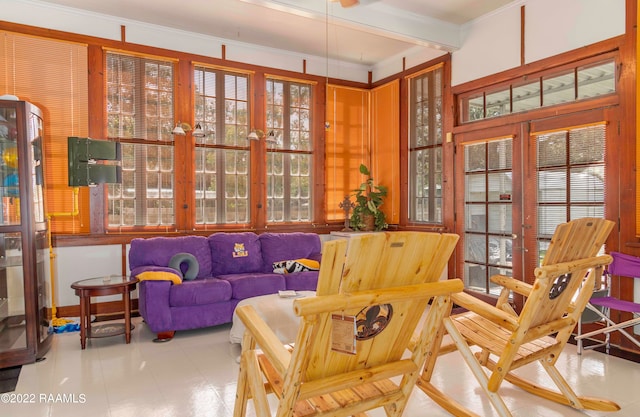 living area featuring a healthy amount of sunlight, crown molding, and light tile flooring