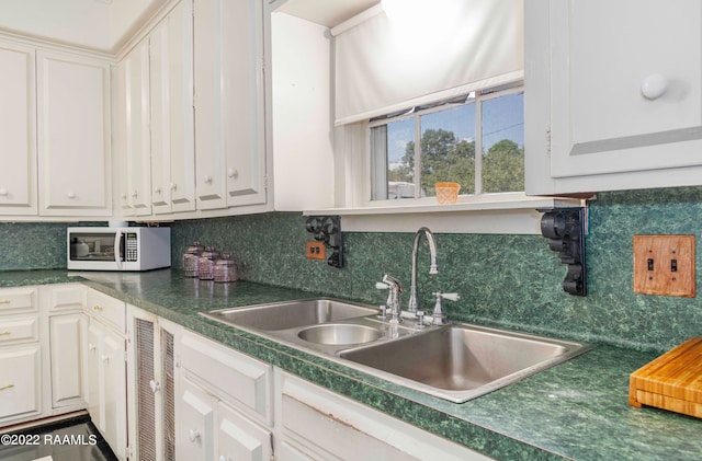 kitchen featuring white cabinets, backsplash, and sink