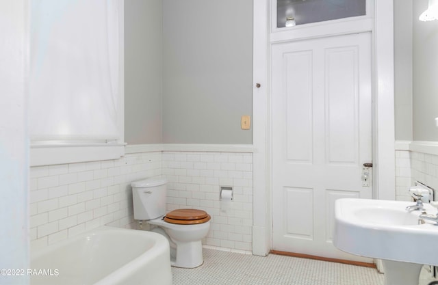 bathroom with a washtub, tile floors, toilet, and tile walls