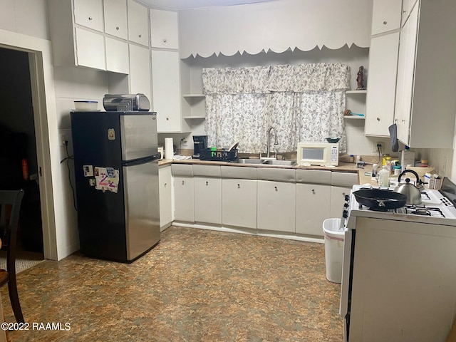 kitchen with white appliances, white cabinetry, and sink