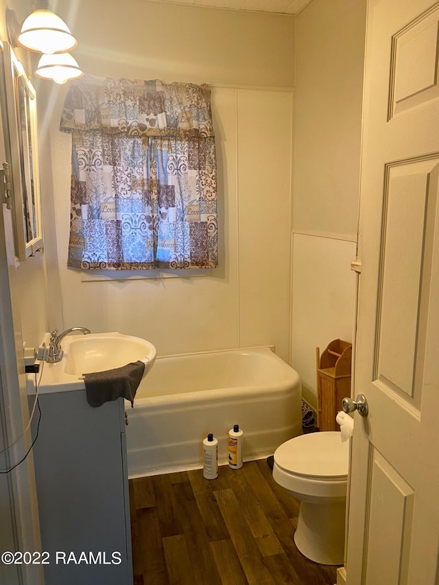 bathroom featuring hardwood / wood-style floors, toilet, vanity, and a tub