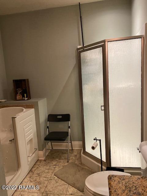 bathroom featuring toilet, tile flooring, and a shower with door