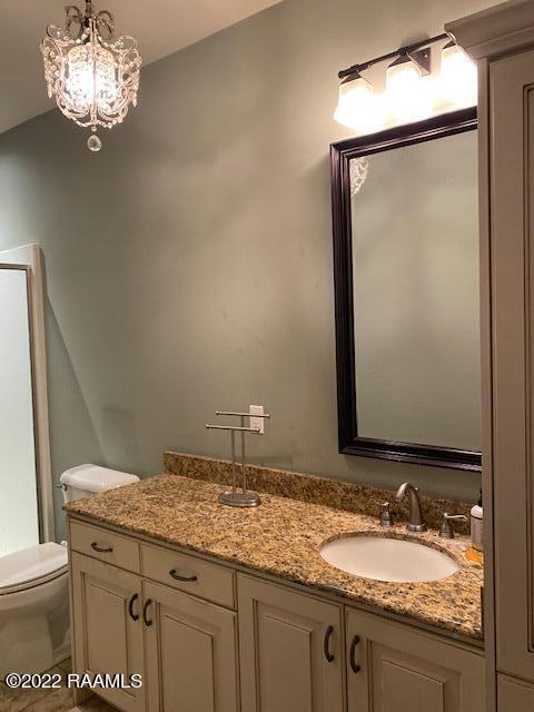 bathroom with toilet, vanity, and an inviting chandelier